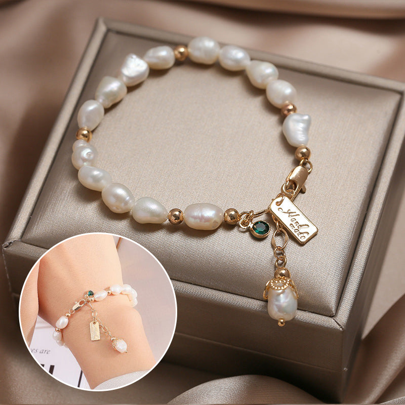 Elegantes Damenarmband mit natürlichen Perlen, goldfarbenen Details und funkelndem Anhänger auf einer Schmuckbox präsentiert