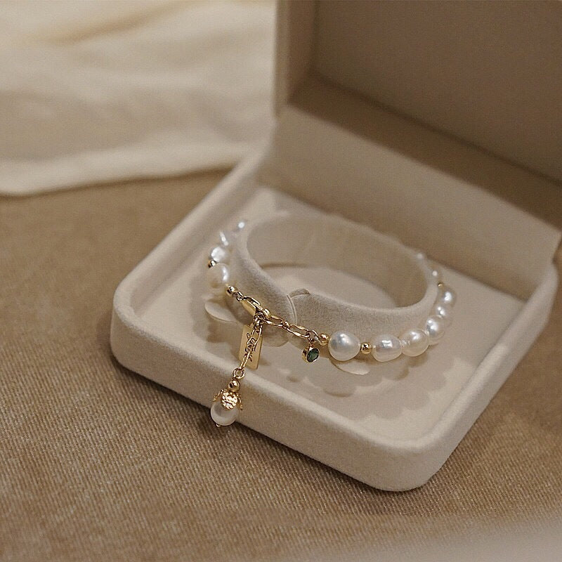 Elegantes Perlenarmband mit goldfarbenen Anhängern und natürlichen Perlen in einer stilvollen Schmuckbox präsentiert – romantischer Damenschmuck mit luxuriöser Ausstrahlung